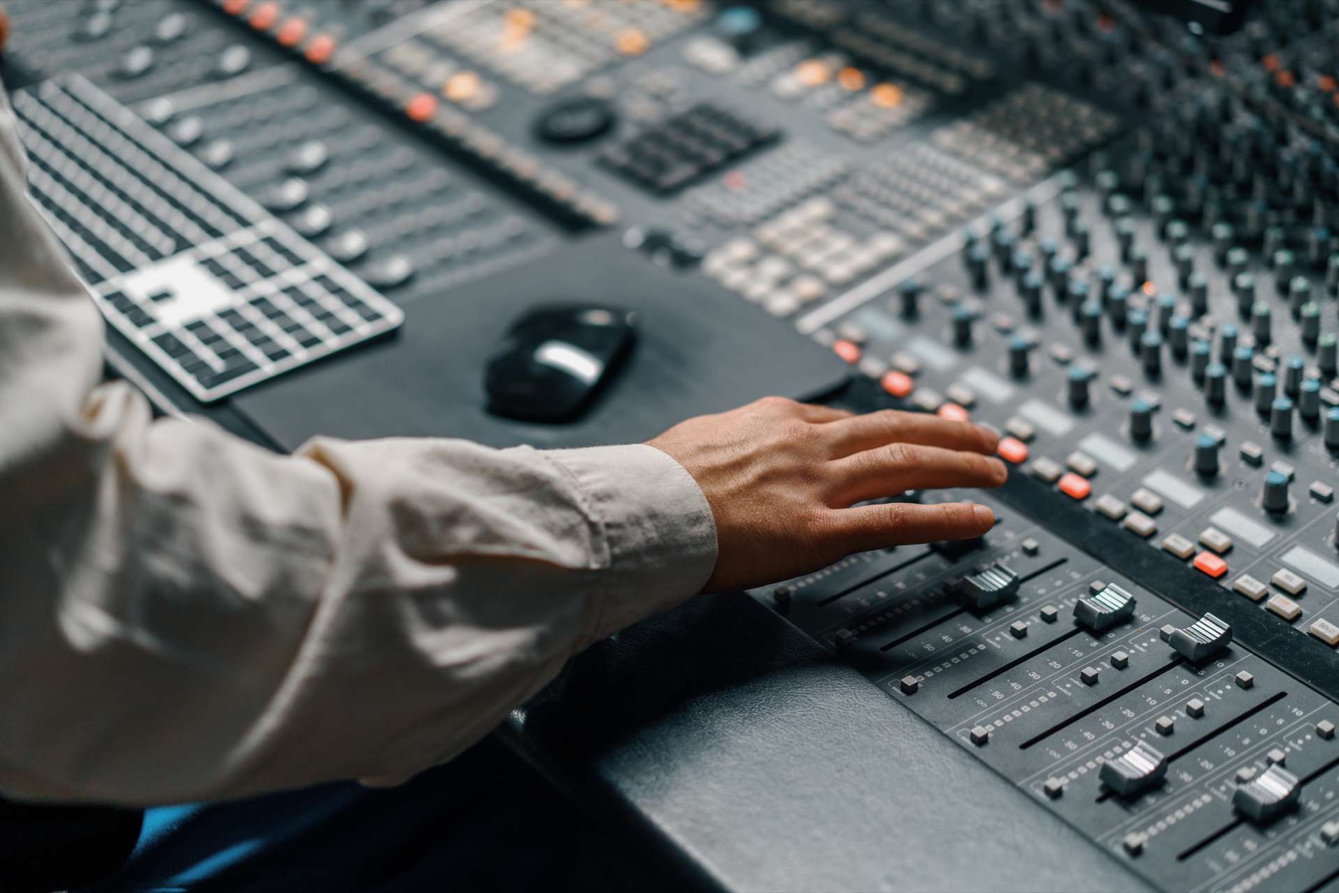 Una mano sobre los faders de una consola de mezcla grande.